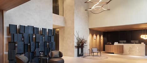 A modern hotel lobby with a reception desk, seating area, and abstract wall art.