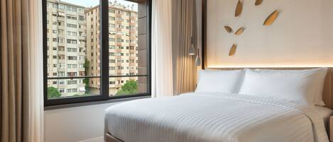 Une chambre d’hôtel avec un grand lit, une fenêtre avec des rideaux et une vue sur un immeuble de grande hauteur.