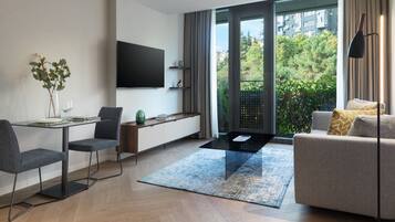 Sala moderna com área de jantar, sofá, TV fixada na parede e vista para o verde lá fora.