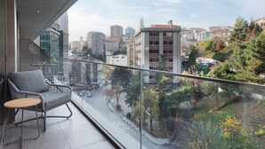 A balcony with a modern chair and table, overlooking a cityscape with buildings and trees. - Marriott Executive Apartments Istanbul Fulya (Istanbul)