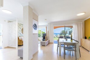 Ein geräumiger Wohnbereich mit großem Fenster und Aussicht auf eine reizvolle Landschaft, ein Essbereich mit Tisch und Stühlen sowie eine gemütliche Sitzecke mit Sofa und Fernseher.