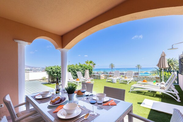 Ein Essbereich mit Tisch für zwei Personen, mit Blick auf Pool und Strand.