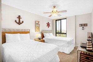 Habitación de hotel con dos camas, ventilador de techo, ventana con vistas y decoración temática náutica.