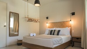A neatly made bed with white linens and two rolled towels, a wooden headboard, a hanging light fixture, and a small bedside table with a lamp. - AGAM Hotel Boutique Bacalar - Adults Only (Bacalar)
