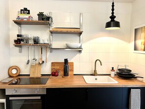 Una cocina moderna con mostradores de madera, horno integrado, un lavamanos y una lámpara colgante.