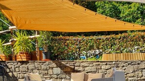 An outdoor patio area with stone flooring, wicker furniture, and a stone wall backdrop. - Studio apartment on 2 floors "Balzone 1" (Toscana)