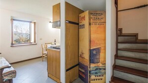 A room with a wooden cabinet, a small table, a chair, and a window with a view of trees. - Studio apartment on 2 floors "Balzone 1" (Toscana)