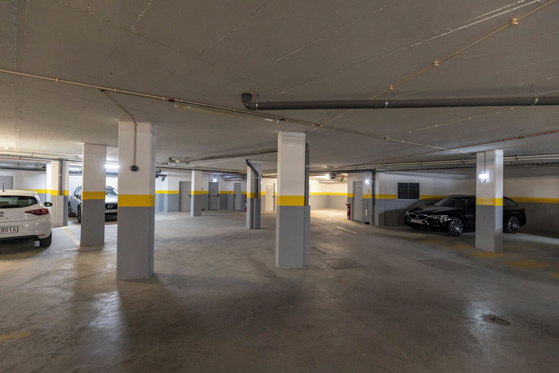 Un estacionamiento subterráneo de varios niveles, con pilares de hormigón y líneas de seguridad amarillas.