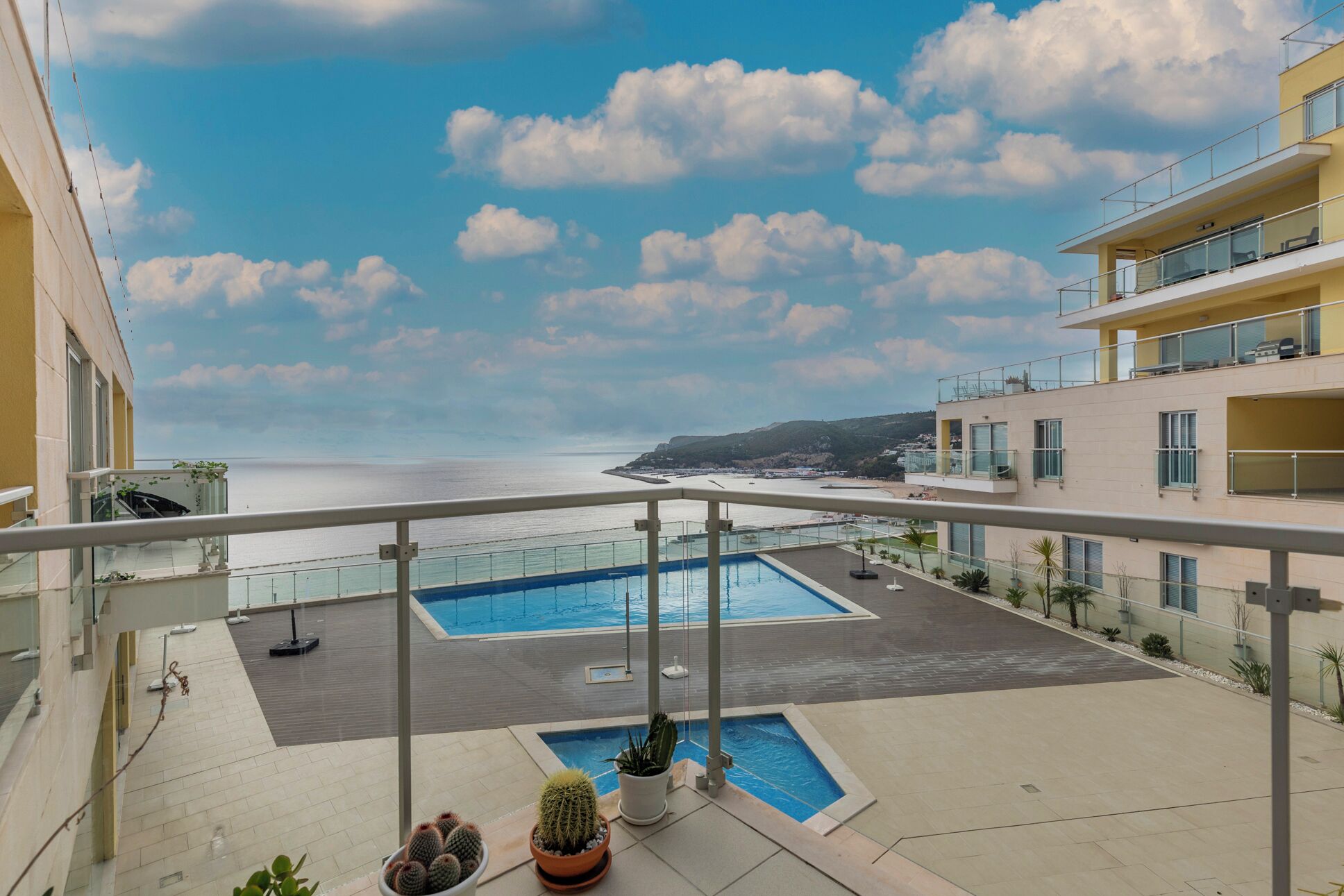 A rooftop pool area with a clear view of the sea and a distant coastline.