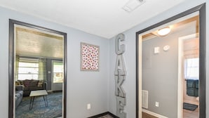 Un pasillo con un letrero que dice 'GATE', una obra de arte con diseños y una sala de estar con sofá y mesa de centro.