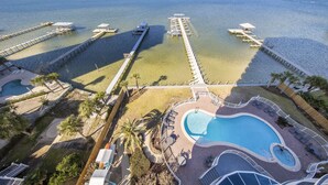 A resort with a swimming pool, docked boats, and a pier extending into the water.