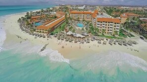 Un complexe hôtelier comprenant plusieurs bâtiments, une plage et une piscine.