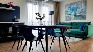 Una sala moderna con un sofá verde, una mesa de comedor con sillas y una zona de cocina.