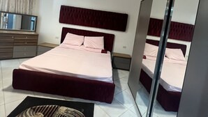 A modern bedroom with a large bed, a mirror, a dresser, and a ceiling light.