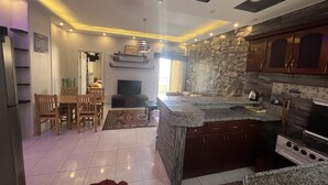 A modern kitchen with granite countertops, a built-in oven, and a stone backsplash.