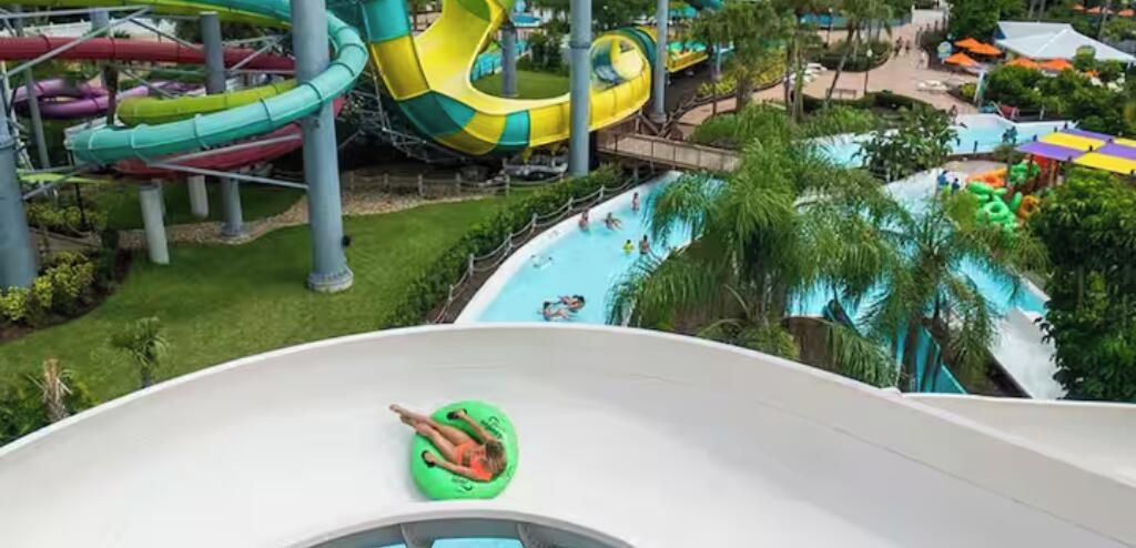 Parque acuático con múltiples toboganes y piscinas, rodeado de vegetación.