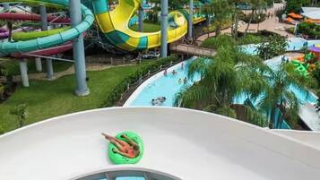 Parque acuático con múltiples toboganes y piscinas, rodeado de vegetación.