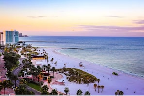 A beachside view with a hotel, palm trees, and a clear sky.
