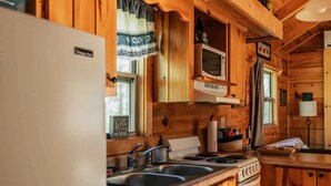 Cuina d'una cabana de fusta amb nevera, fogó, rentavaixelles i microones.
