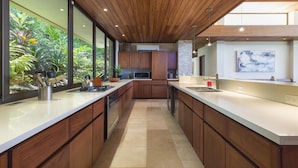 A modern kitchen with wooden cabinets, a stainless steel stove, and a large window overlooking greenery.