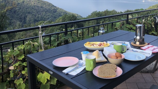 A table set on a balcony overlooking a scenic view of mountains and a lake.