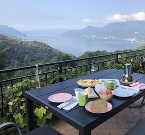 A table set on a balcony overlooking a scenic view of mountains and a lake.