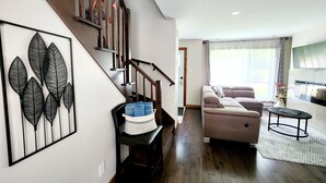 A modern living room with a staircase, a sofa set, and a flat-screen TV.