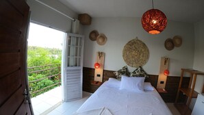 Un dormitorio con cama, ventana, lámpara de techo y vistas a zonas verdes.