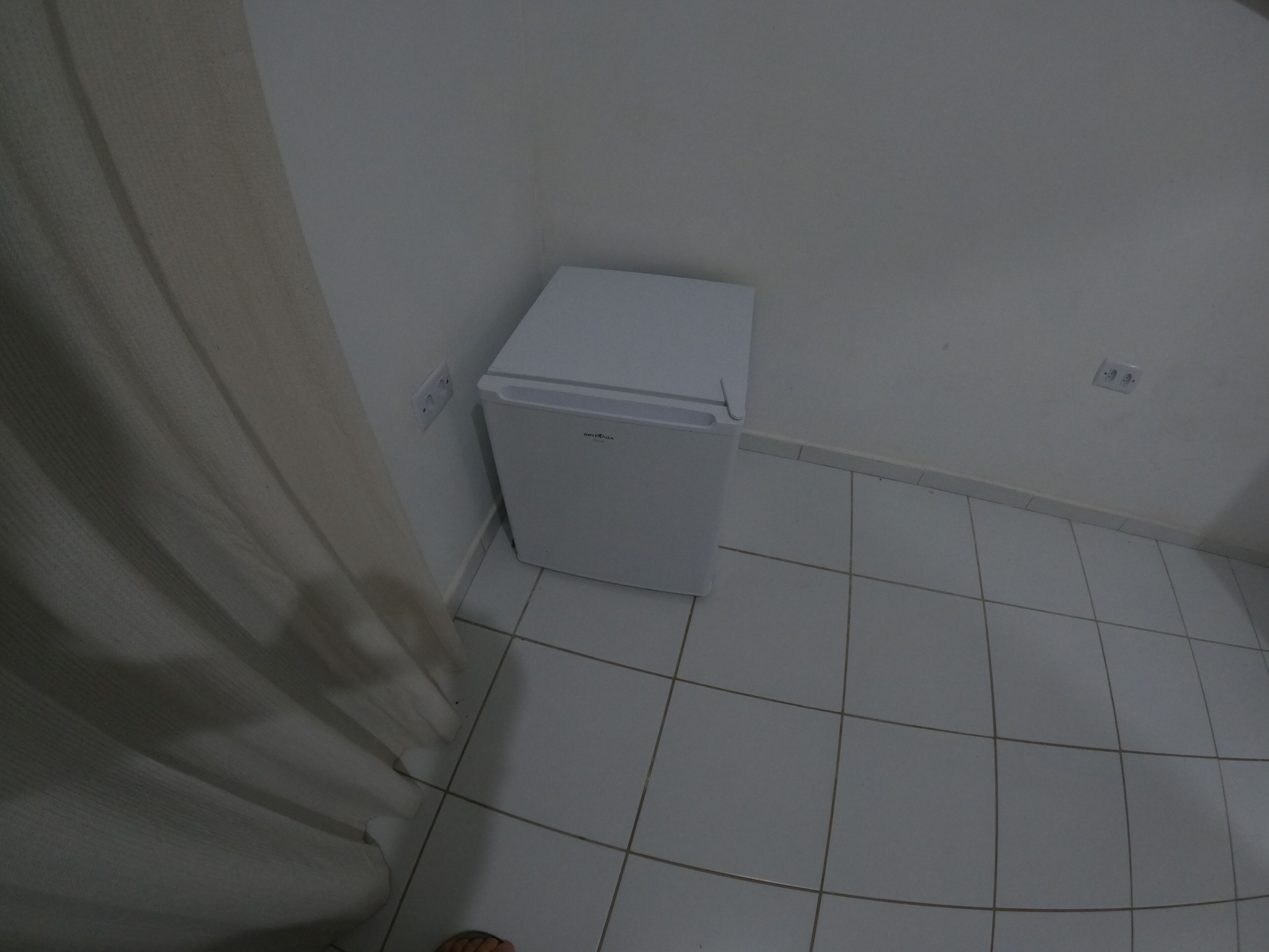 Et lille badeværelse med hvide fliser, toilet, vask og et enkelt rum.