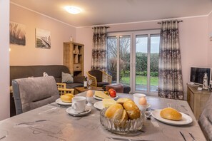 A dining area with a table set for breakfast, including bread, eggs, and butter.