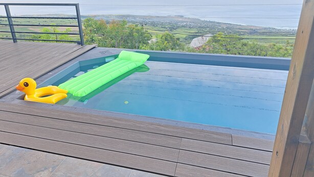 A hot tub with a wooden deck and a view of the ocean.