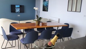 A dining area with a wooden table, blue chairs, a bottle of champagne, and two glasses.