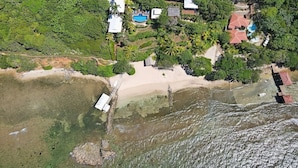Oversigtsbillede af en kystejendom med flere bygninger, en strand og en swimmingpool.