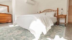 A neatly made bed with a wooden headboard, a bedside table with a lamp, and a dresser with drawers.
