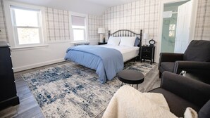 A bedroom with a bed, bedside tables, a chair, a rug, and a window.