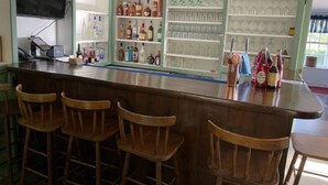 A bar area with wooden chairs, shelves of liquor bottles, and glasses. - Room 08 - King Room  - Handicap accessible (Francestown)