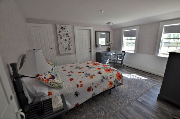 A bedroom with a bed, a desk, a chair, and a dresser.