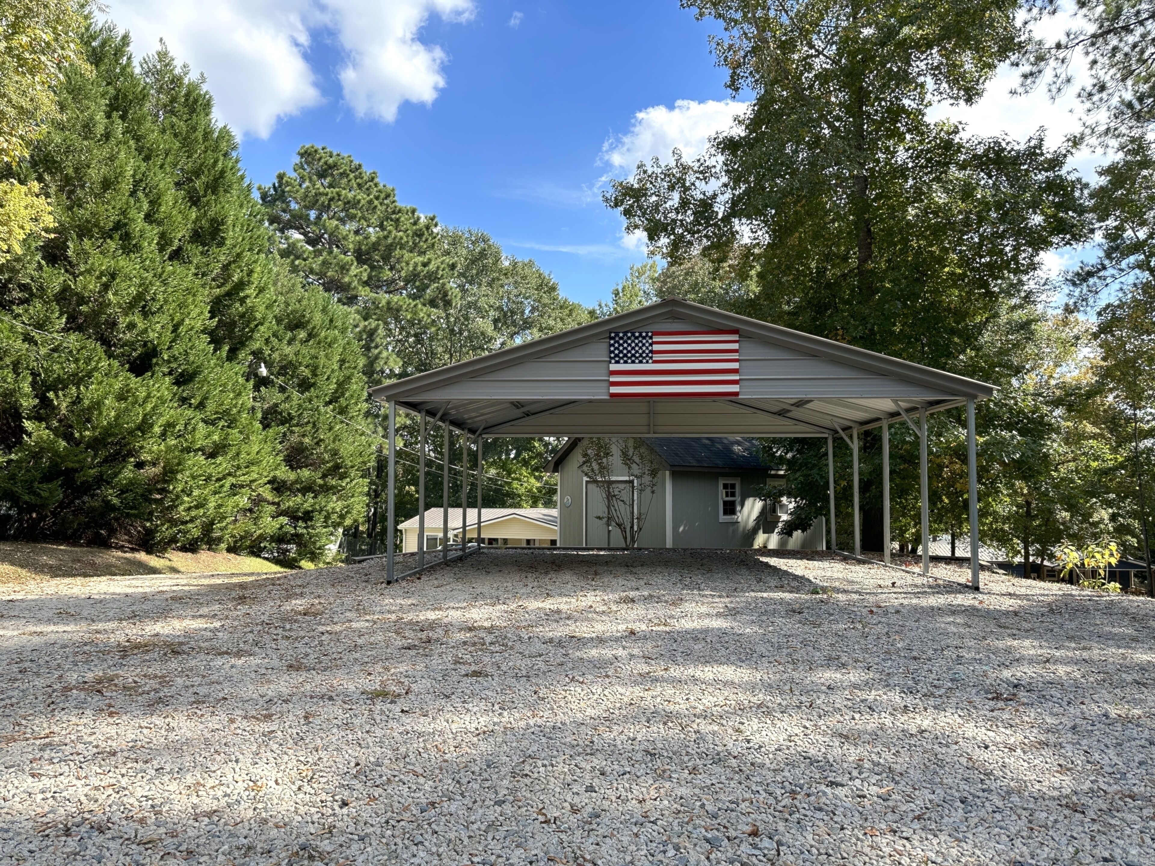Ein überdachter Pavillon mit einer amerikanischen Flagge, umgeben von Bäumen und Kies.