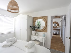 Un dormitorio con cama, cómoda blanca y espejo.