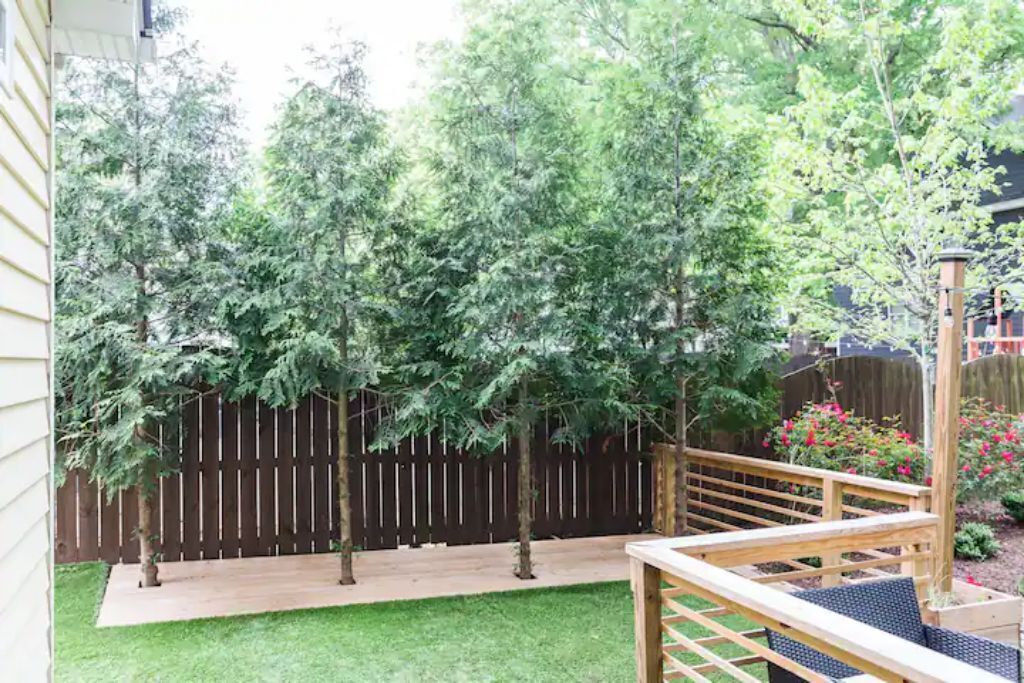 A backyard with a wooden deck, a small lawn, and a wooden fence.