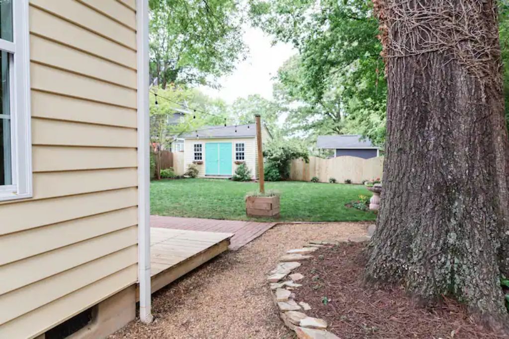 A house with a front yard, a tree, and a small shed in the background.
