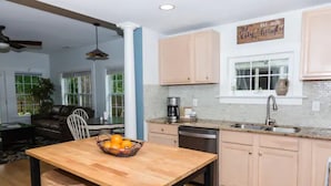 A modern kitchen with a wooden island, light-colored cabinets, and a window with a view. - The City Cottage, pet friendly, walk to shops, food & NCSU (Raleigh)