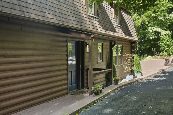 A wooden cabin with a porch, a door, and potted plants.