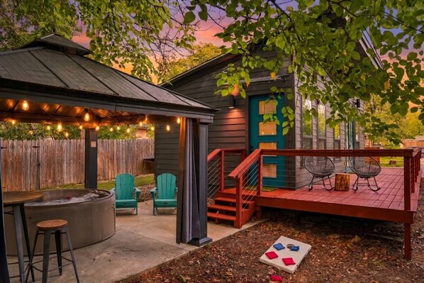 A backyard with a hot tub, outdoor seating, and a deck.