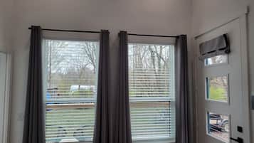 Een kamer met twee ramen, een deur met een hendel, en een klein raam boven de deur.
