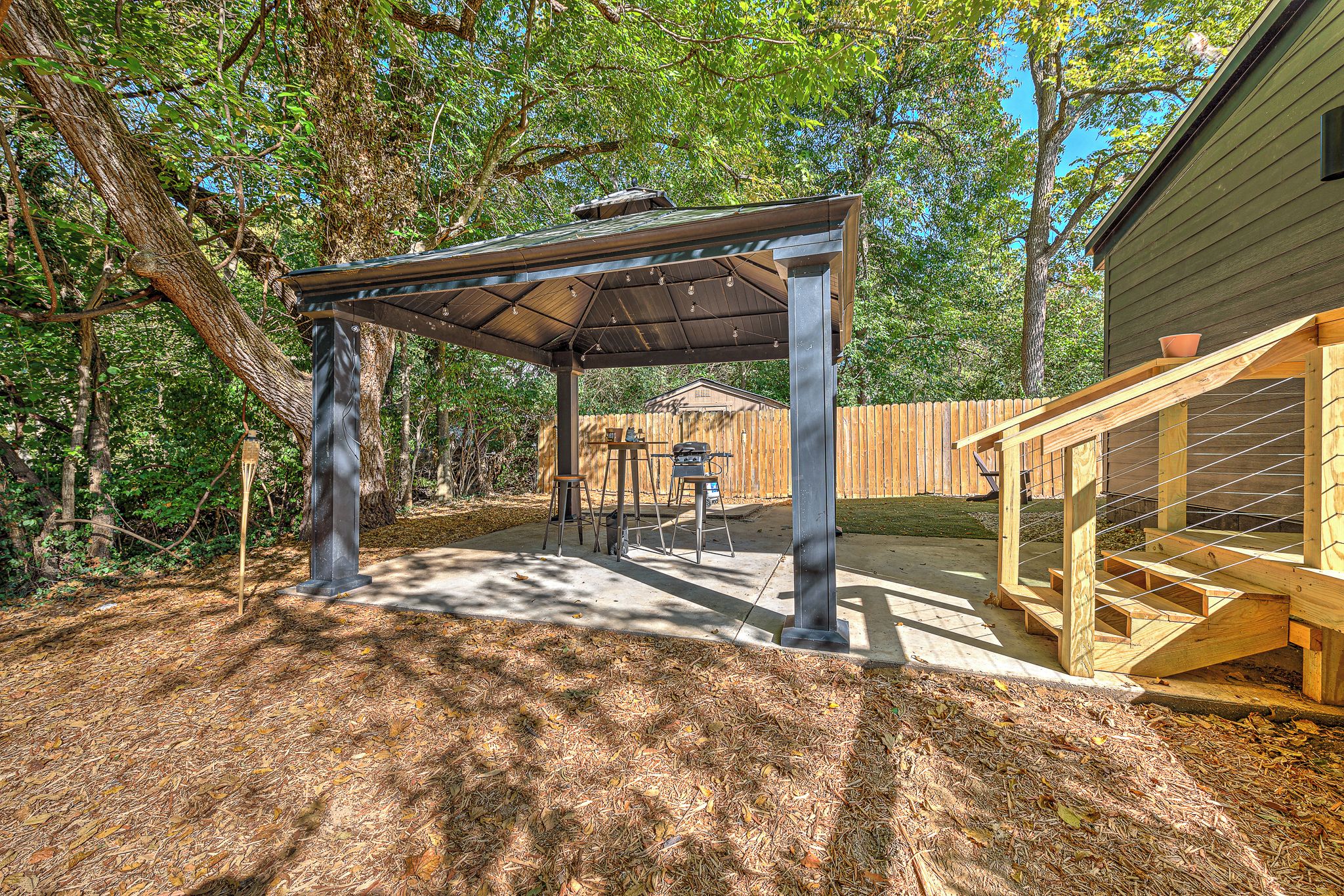 Un espace extérieur aménagé avec une pergola, une terrasse en bois et un jardin clôturé.