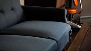 Un salón moderno con un sofá gris oscuro, una mesa de centro de madera y una silla naranja vintage.
