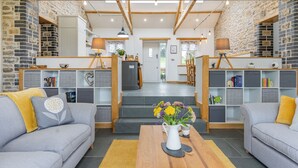 Una sala de estar con chimenea, sofás, una mesa de centro y una estantería.