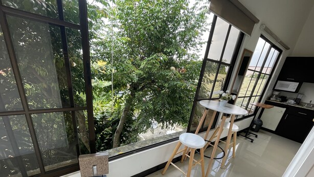 A modern kitchen with large windows, a dining area with stools, and a wooden bench. - Escape a la Ciudad en Nuestro Encantador Apartamento con Todas las Comodidades (San Rafael Arriba de Desamparados)