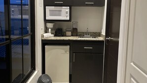 A compact kitchen with a microwave, toaster, and small refrigerator. - Escape a la Ciudad en Nuestro Encantador Apartamento con Todas las Comodidades (San Rafael Arriba de Desamparados)